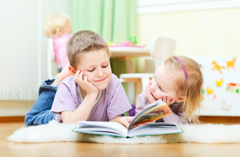 Young child reading a colourful picture book with supportive educator at Starfish Early Learning Centre