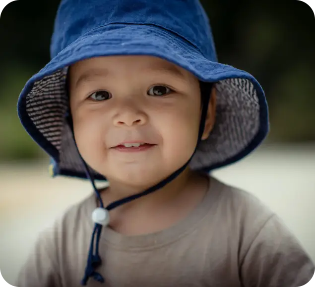 Smiling toddler wearing a blue sun hat outdoors at Starfish Early Learning Centre, highlighting sun safety and nappies policy