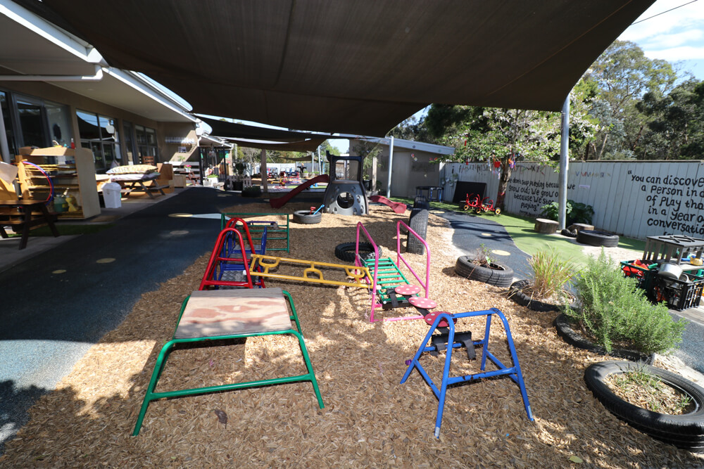 Outdoor childcare playground with climbing frames, balance equipment and shaded play areas for active early learning.