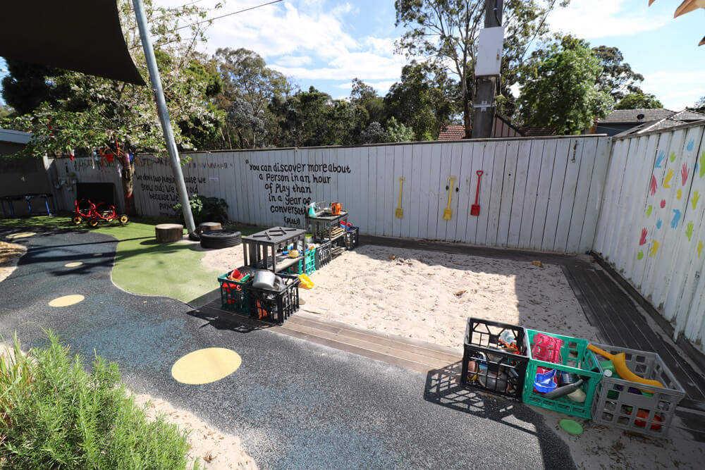 Childcare outdoor sandpit play area with digging tools and natural play equipment supporting early learning.