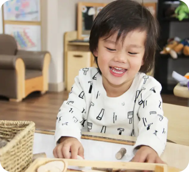 Smiling toddler engaging in play-based learning with wooden sensory toys at Starfish Early Learning Centre classroom