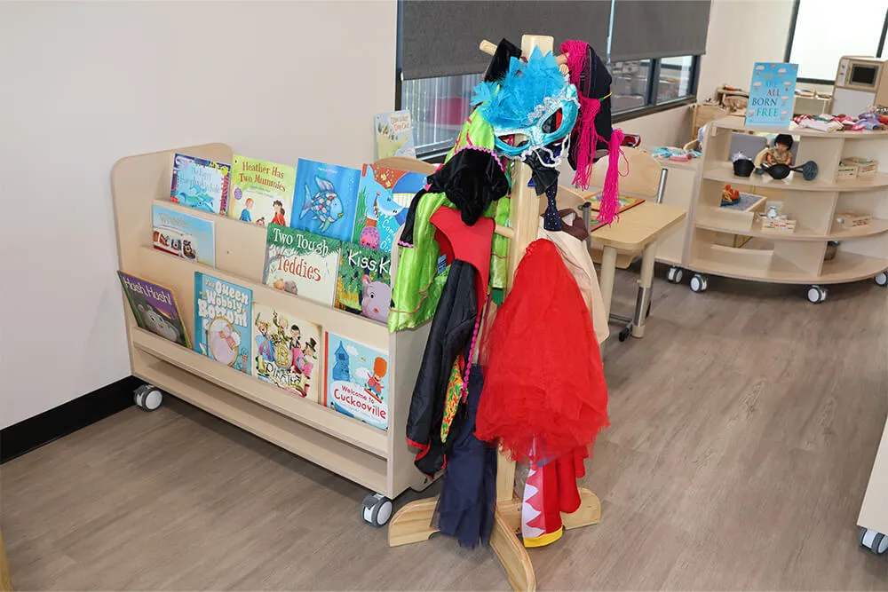Childcare dress-up station with costumes, masks and books encouraging imaginative play in an early learning classroom.