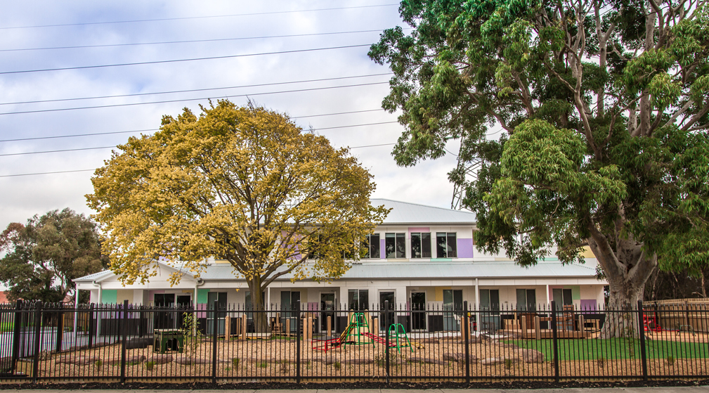 Exterior of Clayton childcare centre with large trees, playground and secure fencing supporting safe early learning.