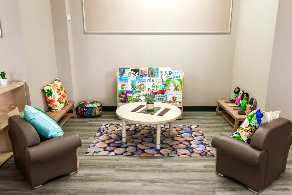 Childcare reading corner with books, soft seating and cushions designed to support calm early learning and kindergarten literacy.