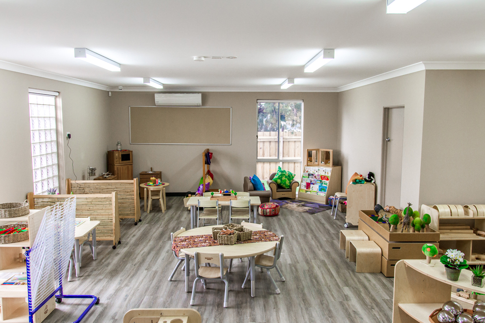 Kindergarten classroom in a childcare centre with learning tables, play areas and natural materials supporting early learning.