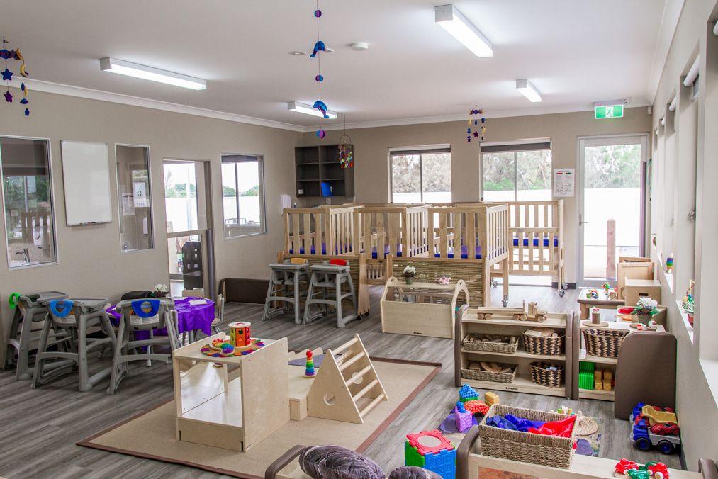 Spacious childcare classroom with play stations, climbing equipment and learning materials for early learning and kindergarten.