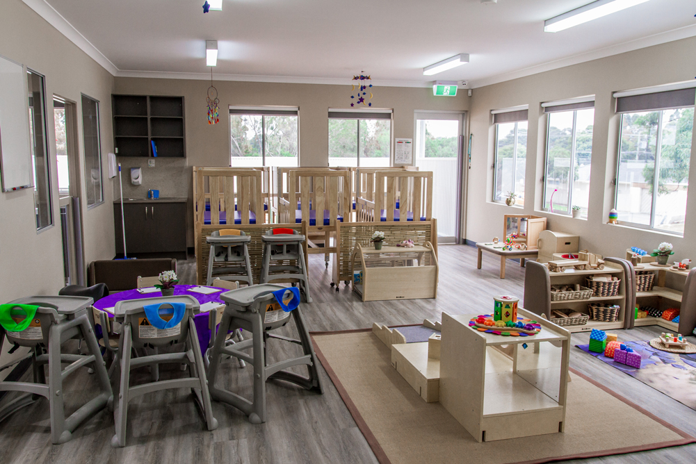 Bright childcare classroom with activity tables, learning materials and play areas supporting early learning and kindergarten readiness.