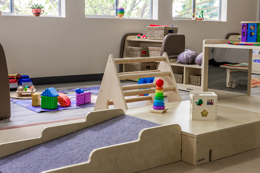 Indoor childcare play area with wooden climbing frame, sensory toys and learning materials supporting safe early learning.