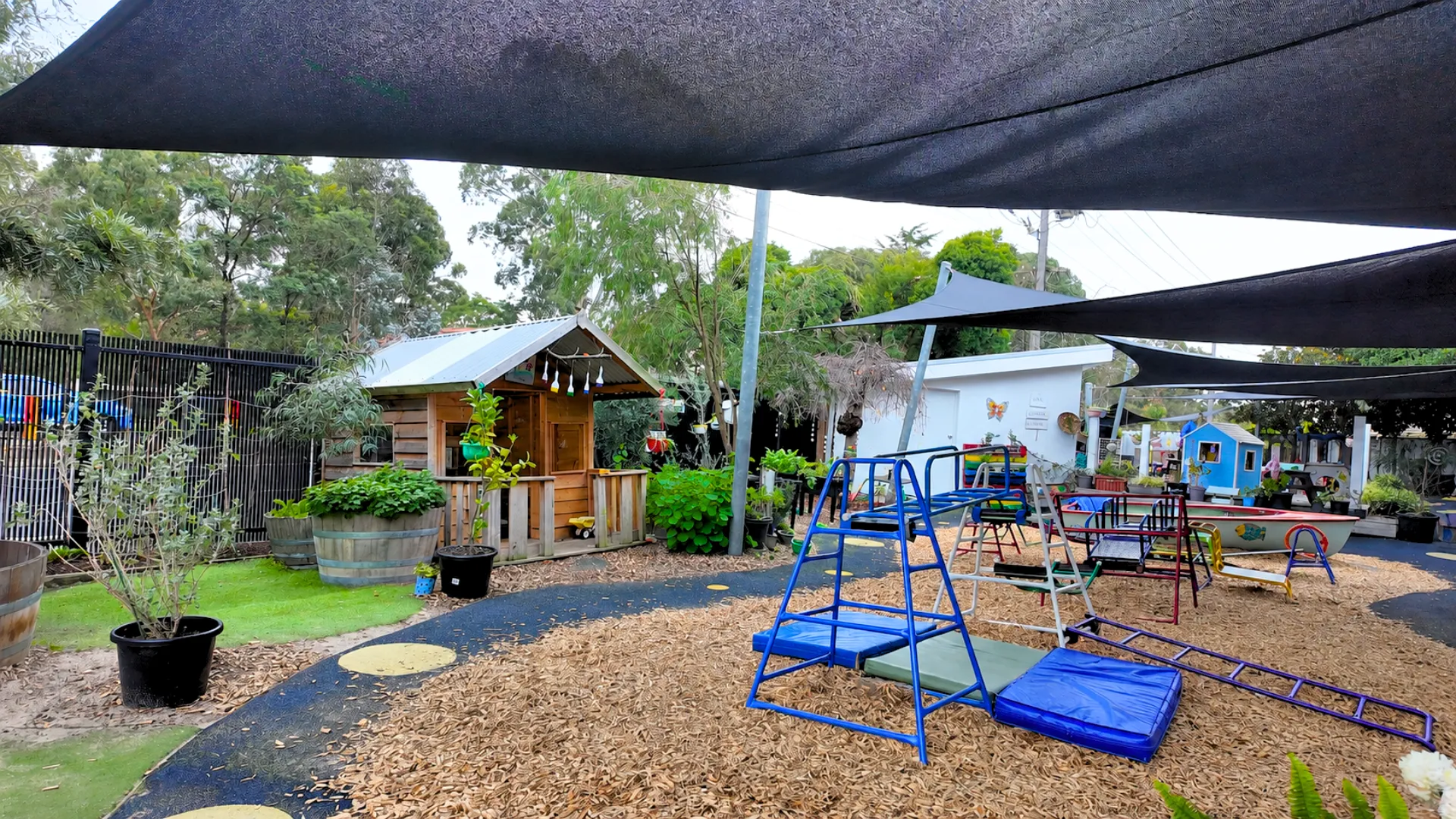 Spacious outdoor playground with climbing equipment, cubby house and shade sails at Starfish ELC Blackburn South