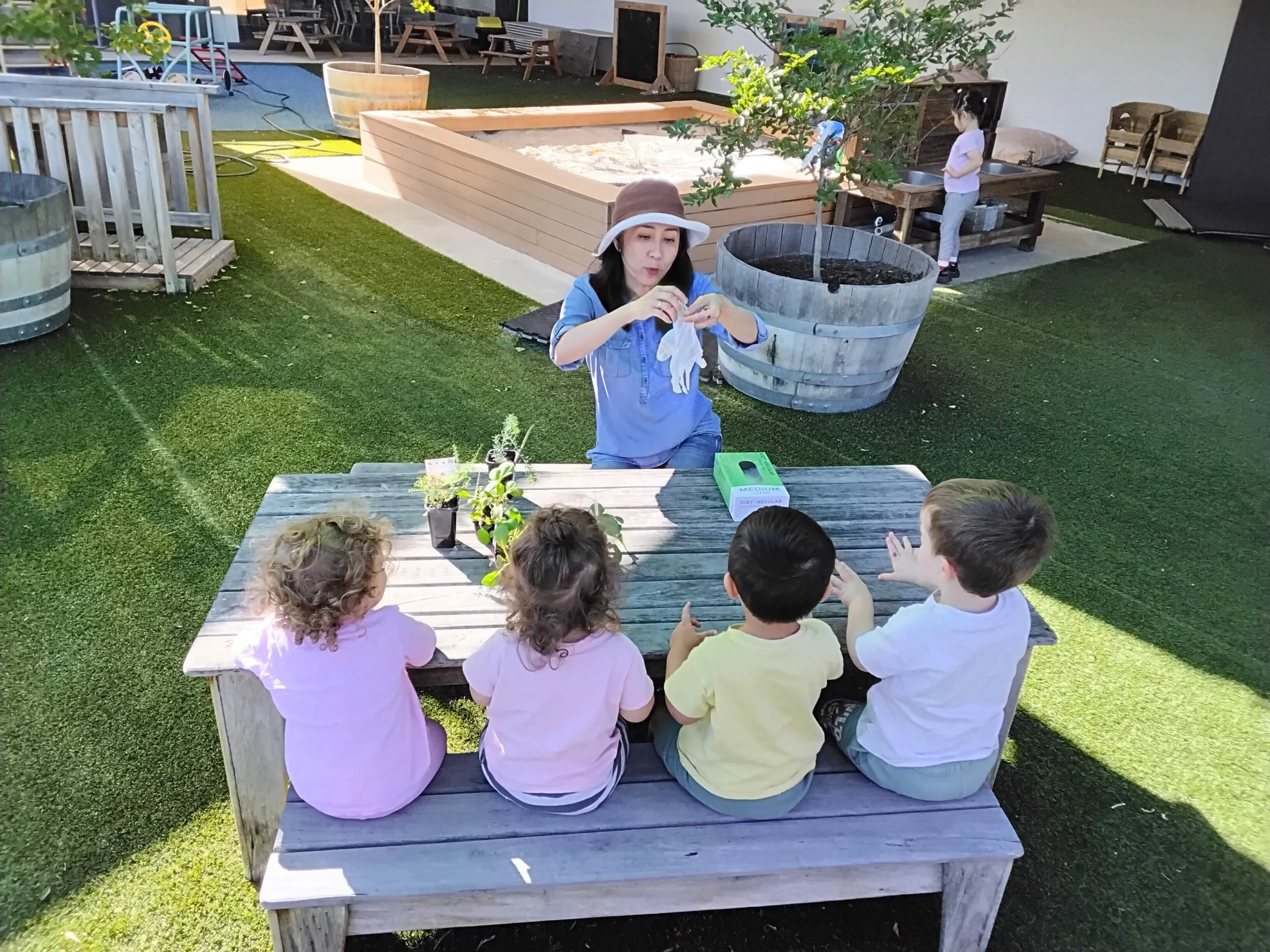 Educator reading a picture book to toddlers during a group early learning activity in a childcare classroom.