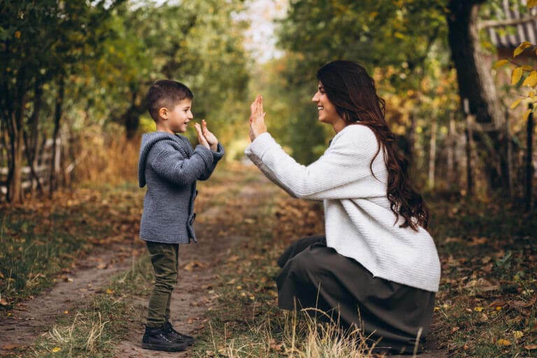 Educator and child sharing a high-five during outdoor play at an early learning childcare setting.