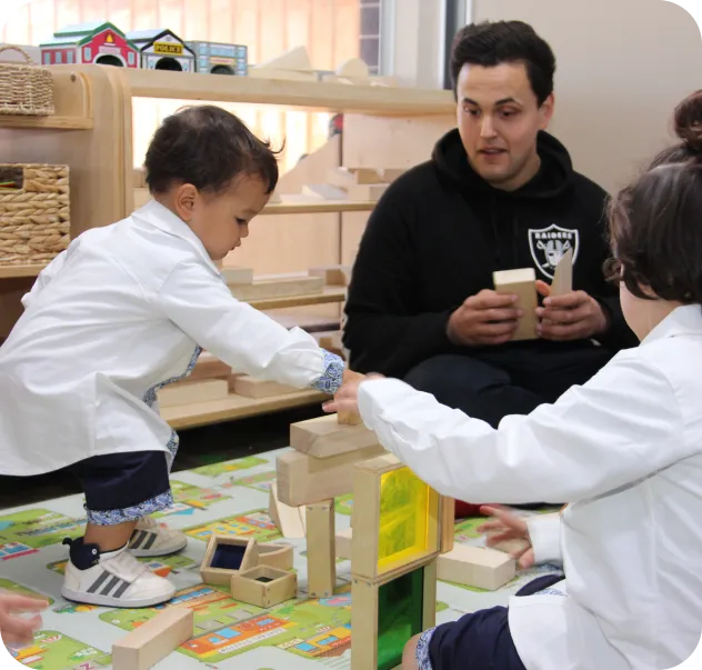 Educator guiding toddlers building wooden block towers in a play-based learning classroom at Starfish Early Learning Centre – Our Philosophy