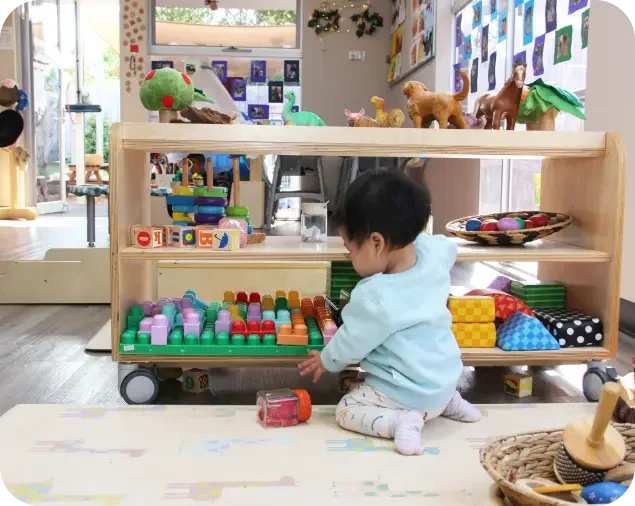 Toddler exploring colourful toys in the nursery room